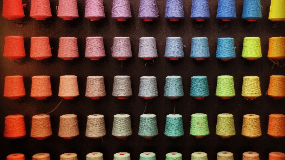 Wall of coloured yarn cones available as stock yarn